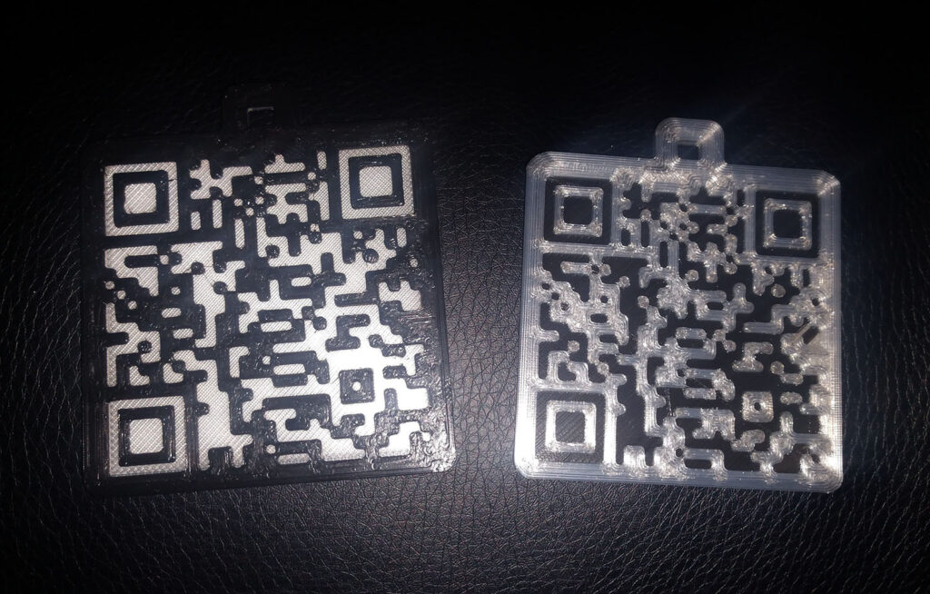 2 black and white 3D printed QR codes sit on a platform